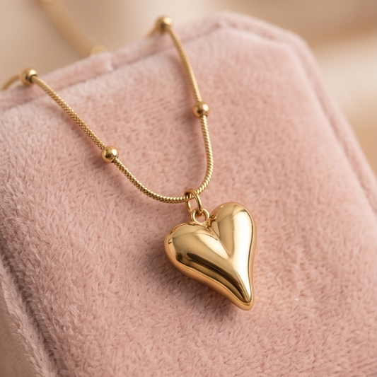 Gold heart-shaped pendant necklace on a pink cushion