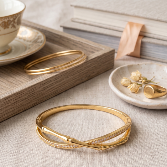 Gold bangles on a textured surface with a cup and saucer in the background