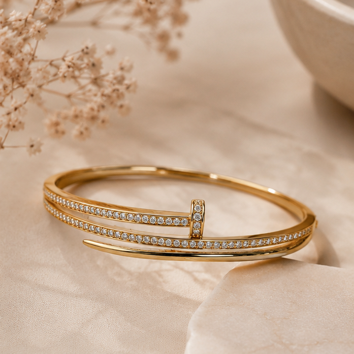 Gold bracelet with crystals on a light background with dried flowers and a bowl.