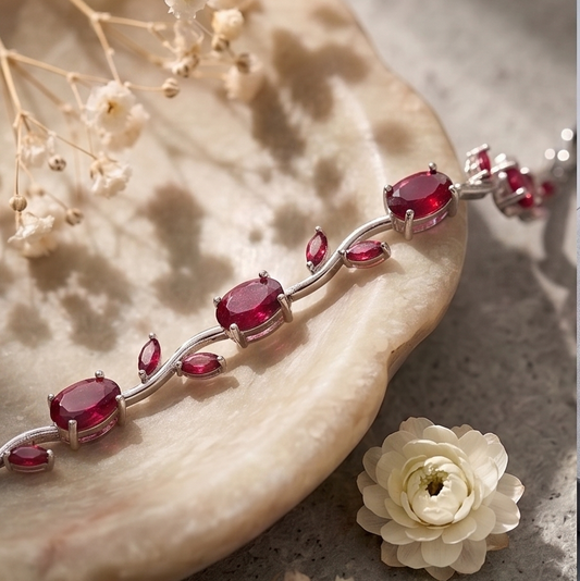 Bracelet with red gemstones on a stone surface with flowers