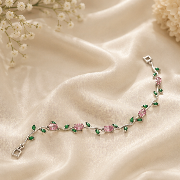 Silver bracelet with pink and green stones on a beige fabric background