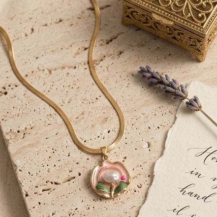 Gold necklace with a pendant on a textured surface with a decorative box and lavender.