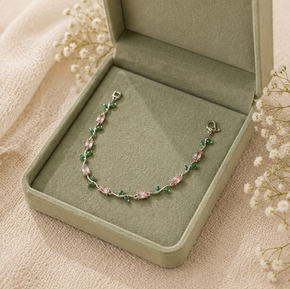Bracelet with pink and green stones in a green jewelry box on a beige fabric background