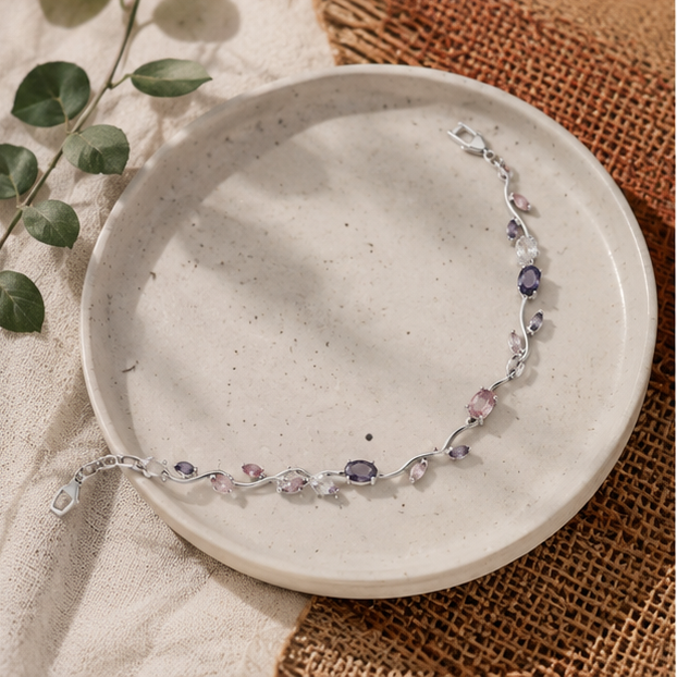 Silver bracelet with purple and pink stones on a ceramic plate with a natural background