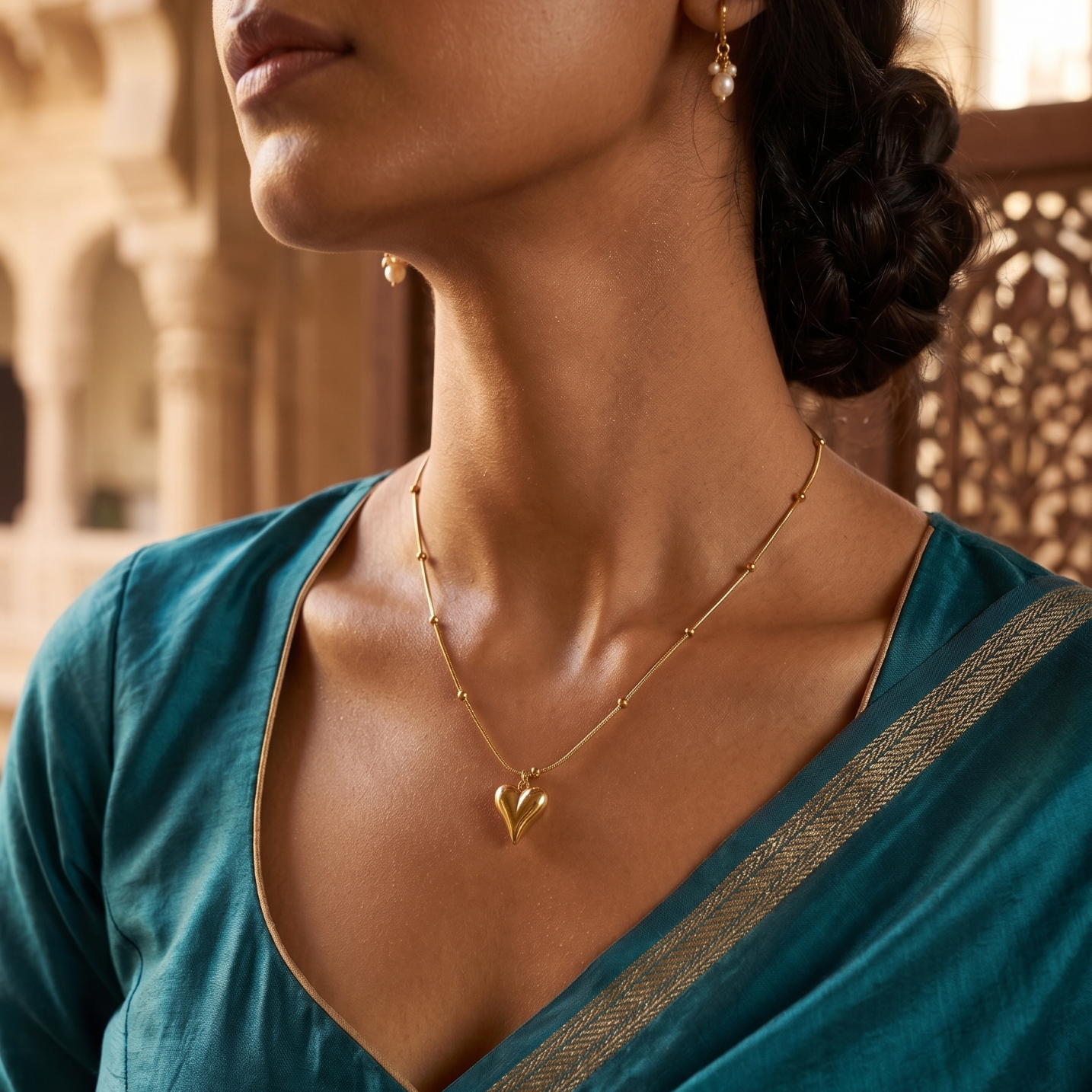 Woman wearing a gold necklace with a heart pendant in an outdoor setting