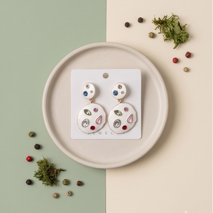 Pair of earrings on a display card with a decorative background