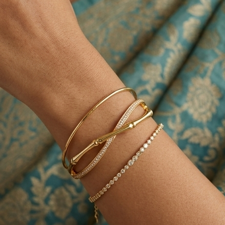 Gold bracelets on a wrist with a patterned fabric background