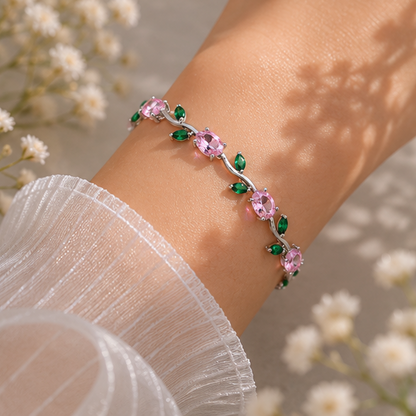 Bracelet with pink and green gemstones on a wrist against a floral background