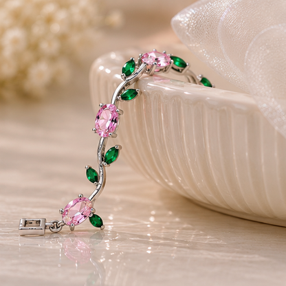 Silver bracelet with pink and green gemstones on a light background