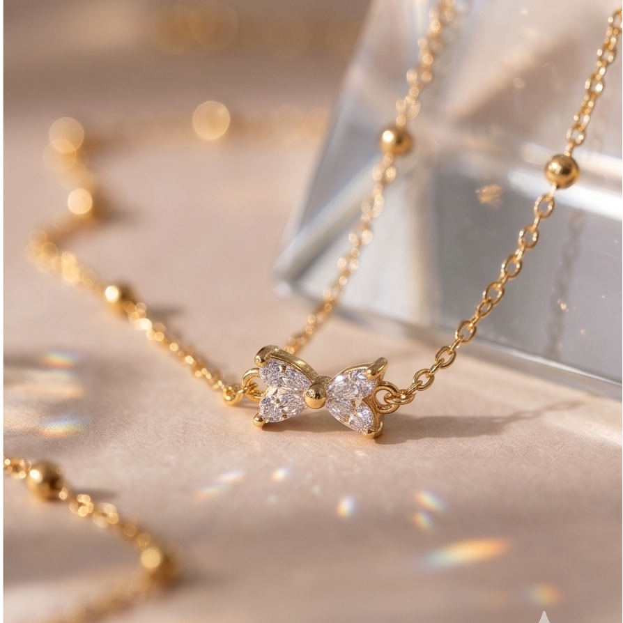 Gold necklace with a bow-shaped pendant on a reflective surface
