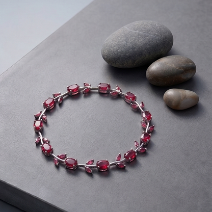 Bracelet with red gemstones on a gray surface with stones